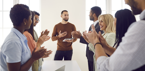 Excited businesspeople applaud successful male speaker or trainer for presentation or lesson at meeting.